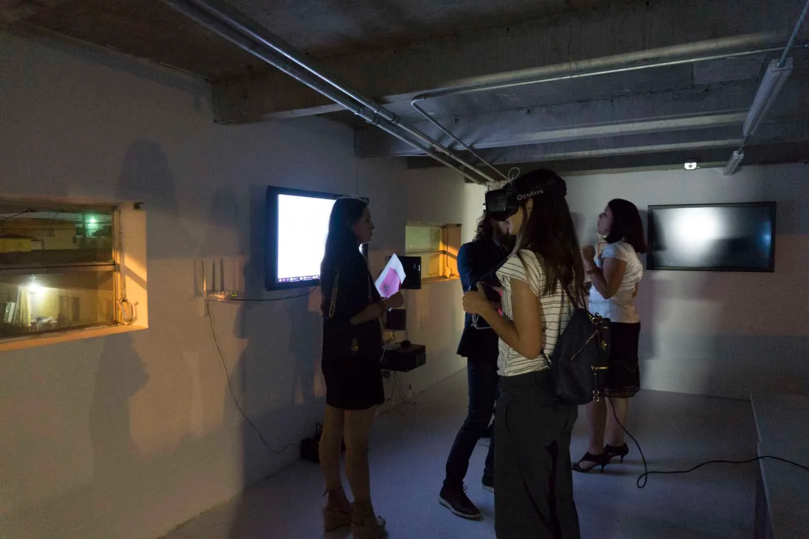People in a room using VR headsets and looking at the screens on the walls, at the Media Under Dystopia 1.0 event