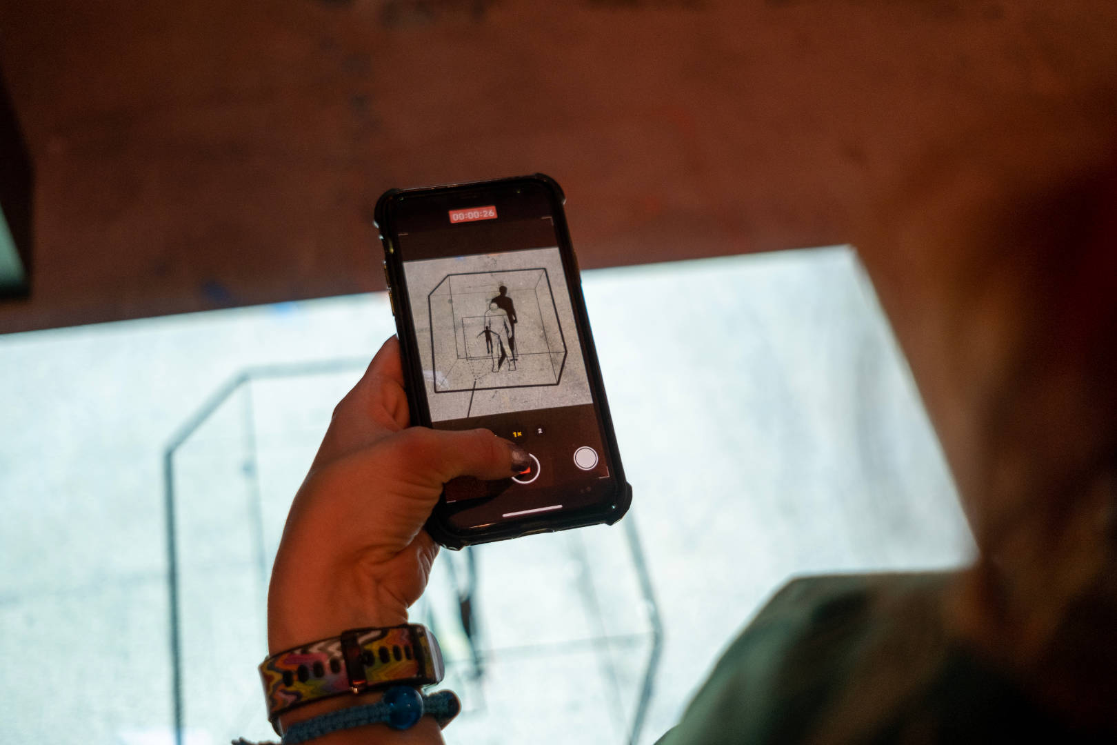 A person taking a picture of the New Extractivism piece projection on the floor